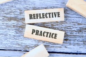 The phrase, "Reflective Practice," is printed on rectangular wooden blocks against a light blue background. 